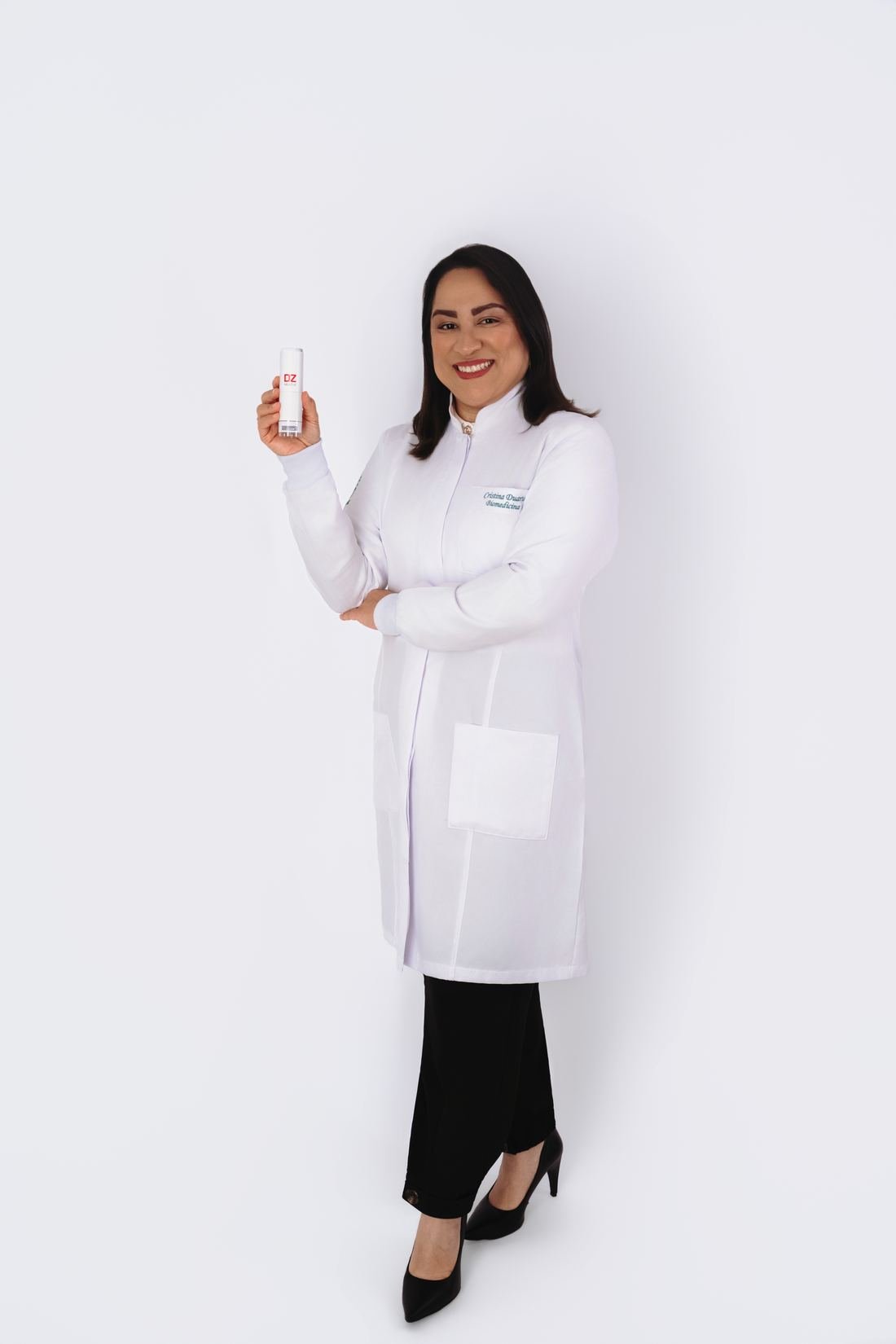 Cristina Duarte de jaleco segurando um dermocosmético